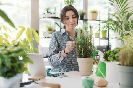 Téléchargez les photos : Jeune femme détendue prenant soin de ses plantes à la maison, passe-temps et concept de jardinage - en image libre de droit