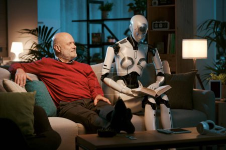 Téléchargez les photos : Homme âgé et robot androïde femme assis sur le canapé à la maison, ils lisent un livre ensemble, concept de relations homme-robot - en image libre de droit