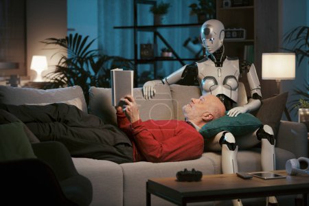 Foto de Hombre mayor y robot androide femenino cariñoso sentado en el sofá en casa, están leyendo un libro juntos, concepto de relaciones hombre-robot - Imagen libre de derechos