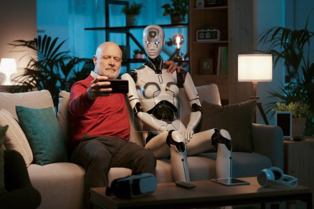 Foto de Hombre mayor sonriente sentado en el sofá con su robot humanoide AI y tomando fotos con su teléfono inteligente - Imagen libre de derechos