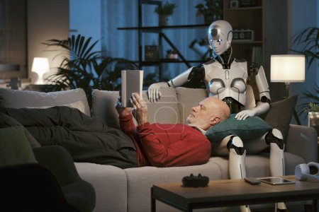Photo for Senior man and caring female android robot sitting on the couch at home, they are reading a book together, human-robot relationships concept - Royalty Free Image