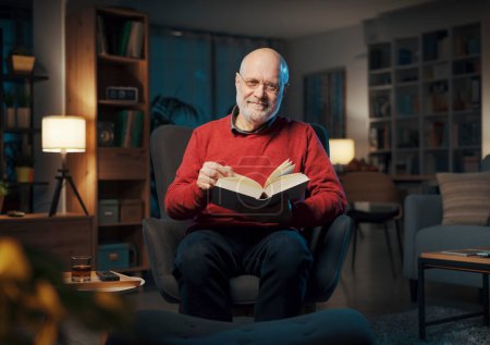 Foto de Hombre mayor sentado en el sillón y leyendo un libro, conocimiento y concepto de aprendizaje - Imagen libre de derechos