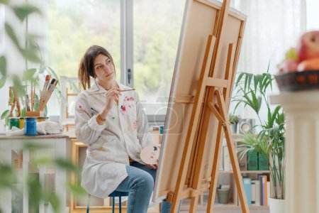 Foto de Joven mujer creativa pintura sobre lienzo en el estudio de arte, arte y concepto de hobby - Imagen libre de derechos
