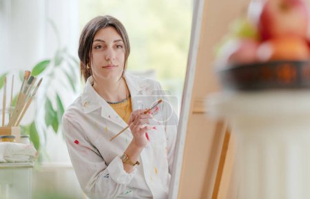 Foto de Artista femenina creativa que trabaja en el estudio de arte, está pintando sobre lienzo - Imagen libre de derechos