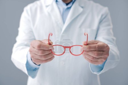Photo for Eye care specialist holding new prescription glasses - Royalty Free Image