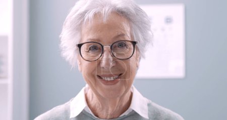 Foto de Mujer mayor sonriente con gafas graduadas y mirando a la cámara, concepto de cuidado ocular - Imagen libre de derechos