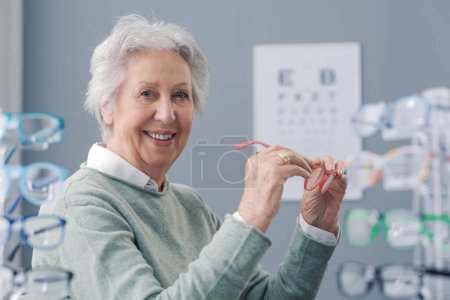 Foto de Mujer mayor probando nuevas gafas graduadas y sonriente, concepto de cuidado ocular - Imagen libre de derechos