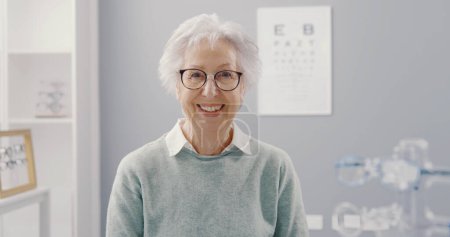 Foto de Mujer mayor sonriente con gafas graduadas y mirando a la cámara, concepto de cuidado ocular - Imagen libre de derechos