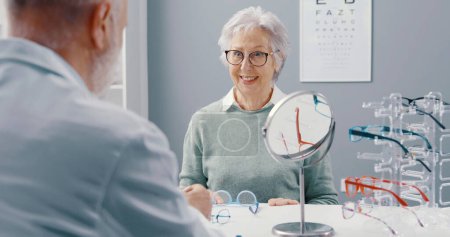 Foto de Feliz mujer mayor en la tienda de óptica, ella está usando sus nuevas gafas - Imagen libre de derechos