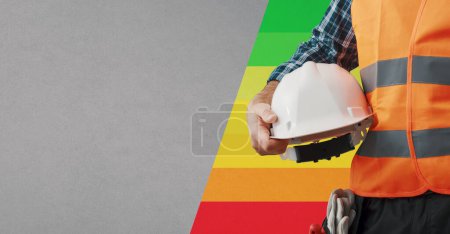 Téléchargez les photos : Travailleur de la construction tenant un casque de sécurité et un indice d'efficacité énergétique du bâtiment, bannière avec espace de copie - en image libre de droit