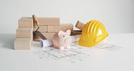 Photo for Bricks, work tools, piggy bank and house plan: building and construction project - Royalty Free Image