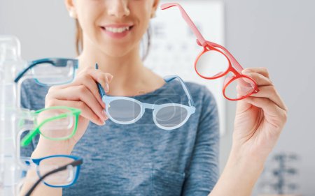 Téléchargez les photos : Happy woman choisir une nouvelle paire de lunettes à la boutique de lunettes, soins des yeux et concept de mode - en image libre de droit