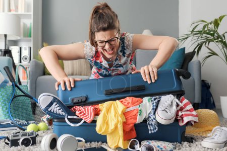 Gestresste, wütende Frau packt ihre Kleidung für den Urlaub ein und füllt ihren Rollkoffer
