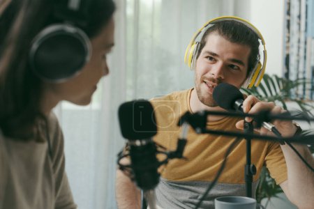 Foto de Young man and woman wearing headphones and doing a live podcast for their channel, communication and technology concept - Imagen libre de derechos