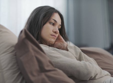 Photo for Sad young woman sitting on the bed at home, she is lonely and depressed - Royalty Free Image