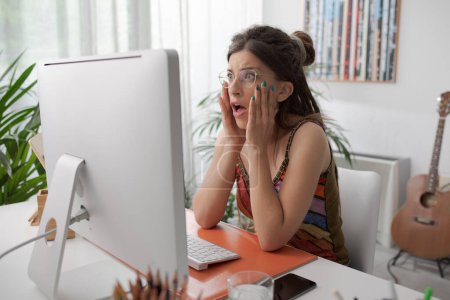 Téléchargez les photos : Choqué femme paniquée assis au bureau et ayant des problèmes informatiques - en image libre de droit
