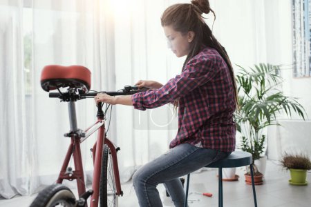 Photo for Young confident woman repairing her bicycle at home - Royalty Free Image