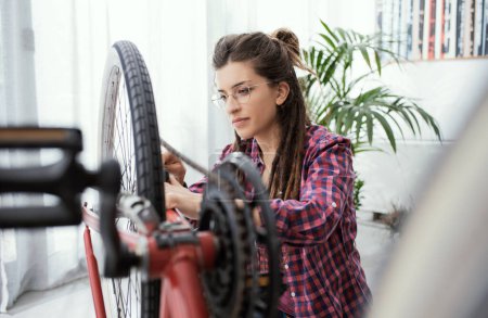 Photo for Young confident woman repairing her bicycle at home - Royalty Free Image