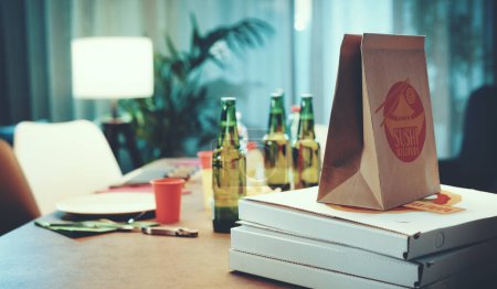 Téléchargez les photos : Livraison rapide à domicile : boîtes à pizza, sushis dans un sac et boissons sur une table - en image libre de droit