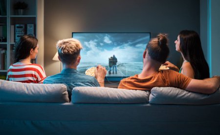 Foto de Grupo de amigos sentados en el sofá en casa y viendo películas juntos - Imagen libre de derechos