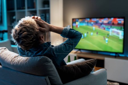 Photo for Disappointed man watching his football team losing the match on TV - Royalty Free Image