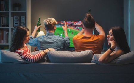 Gelangweilte Mädchen reden und tratschen zusammen, während ihre Freunde Fußball im Fernsehen gucken