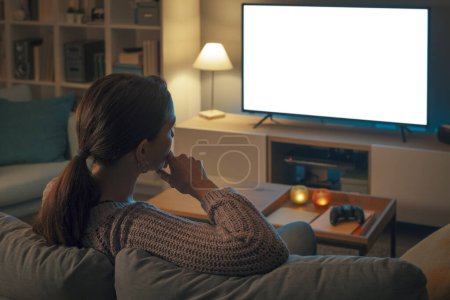 Photo for Woman relaxing on the couch at home and watching television, screen mock-up - Royalty Free Image