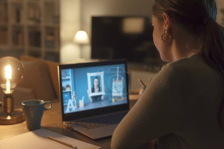 Foto de Mujer conectándose con su portátil y tomando clases de arte en línea, un profesor está mostrando un marco y hablando en un webinar - Imagen libre de derechos