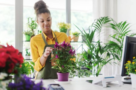 Téléchargez les photos : Jeune femme afro-américaine travaillant dans son magasin de fleurs, concept de petite entreprise - en image libre de droit