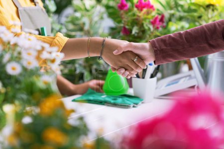 Photo for Florist and customer shaking hands at the plant shop, hands close up - Royalty Free Image