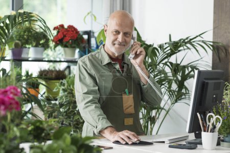 Foto de Florista profesional que trabaja en su tienda, está recibiendo pedidos por teléfono y usando una computadora - Imagen libre de derechos