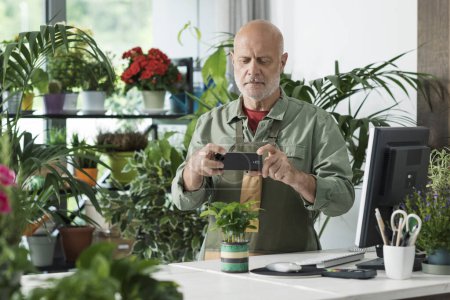 Photo for Professional florist taking pictures of a plant and sharing online, he is selling plants online - Royalty Free Image