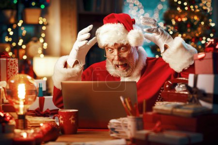 Téléchargez les photos : Choqué a souligné Père Noël ayant des problèmes avec son ordinateur portable la veille de Noël - en image libre de droit