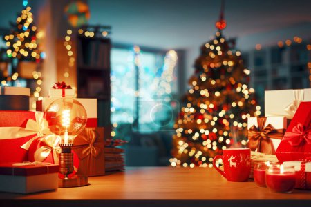 Téléchargez les photos : Cadeaux et décorations sur une table, arbre de Noël et intérieur de la maison en arrière-plan, espace de copie - en image libre de droit