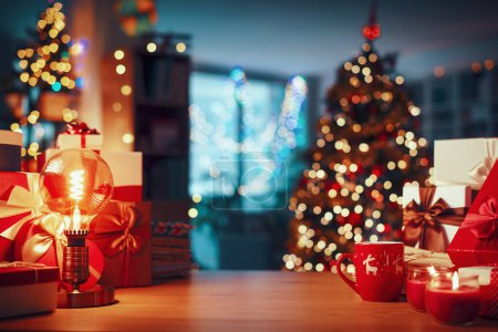 Téléchargez les photos : Cadeaux et décorations sur une table, arbre de Noël et intérieur de la maison en arrière-plan, espace de copie - en image libre de droit