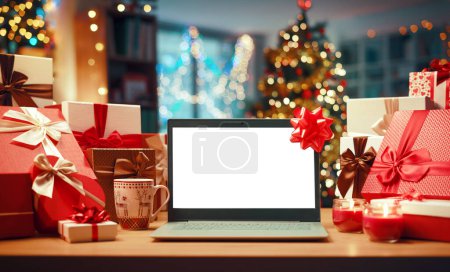 Téléchargez les photos : Ordinateur portable avec écran vierge sur un bureau, cadeaux et décorations de Noël : concept de magasinage et vacances en ligne - en image libre de droit