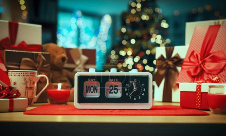 Foto de Reloj despertador vintage en una mesa que muestra la hora y la fecha y el interior de la casa decorada: es Navidad - Imagen libre de derechos