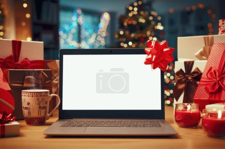 Foto de Ordenador portátil con pantalla en blanco en un escritorio, regalos de Navidad y decoraciones: compras en línea y concepto de vacaciones - Imagen libre de derechos