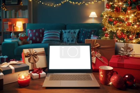 Foto de Interior del hogar con muchos regalos de Navidad y portátil con pantalla en blanco - Imagen libre de derechos