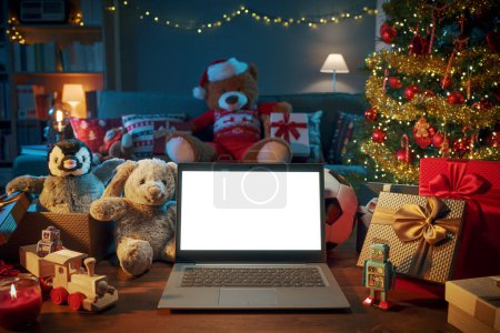 Téléchargez les photos : Intérieur de la maison avec de nombreux cadeaux de Noël et ordinateur portable avec écran vierge - en image libre de droit