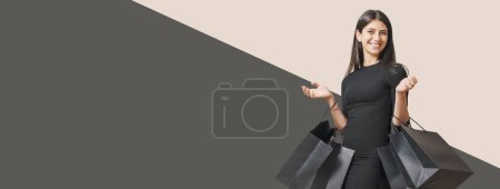 Foto de Feliz mujer elegante haciendo compras el Viernes Negro, ella está llevando bolsas negras, pancarta con espacio para copiar - Imagen libre de derechos