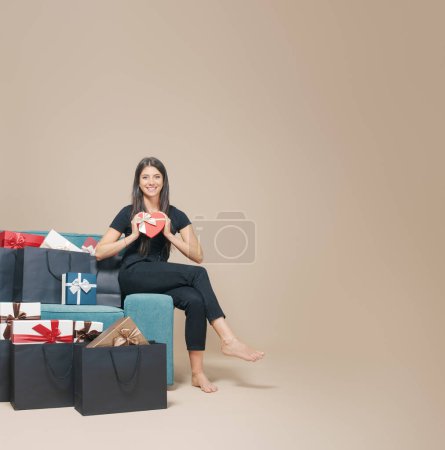 Téléchargez les photos : Femme heureuse à la maison et de nombreux cadeaux dans des sacs à provisions noirs - en image libre de droit
