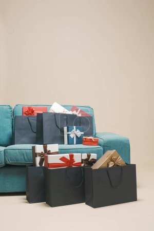 Téléchargez les photos : De nombreux cadeaux et sacs à provisions à la maison à côté d'un canapé, concept de vente et de fête - en image libre de droit