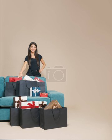 Photo for Happy woman at home and many gifts in black shopping bags - Royalty Free Image