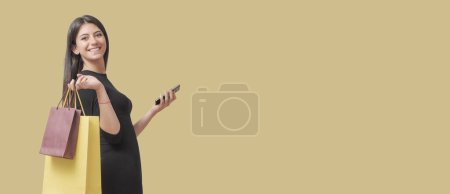 Foto de Feliz mujer de moda sosteniendo bolsas de compras y un teléfono inteligente, ventas y descuentos concepto - Imagen libre de derechos