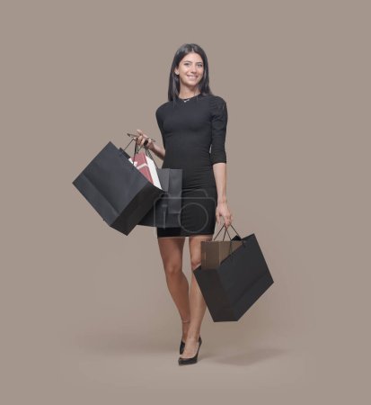 Foto de Joven mujer de moda sosteniendo bolsas de compras negras y un teléfono inteligente, ella está haciendo compras en Viernes Negro - Imagen libre de derechos