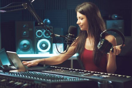 Téléchargez les photos : Jeune femme travaillant dans le studio d'enregistrement, elle utilise une tablette tactile et enregistre des chansons - en image libre de droit
