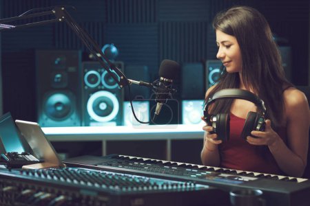 Téléchargez les photos : Jeune musicienne créative travaillant dans le studio d'enregistrement, elle tient des écouteurs - en image libre de droit