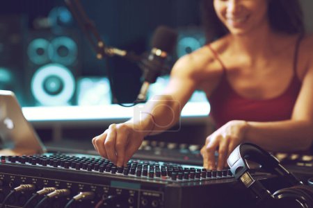 Téléchargez les photos : Jeune ingénieur du son dans le studio d'enregistrement, elle installe le mixeur, les mains fermées - en image libre de droit