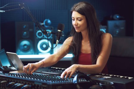 Photo for Young creative musician working in the recording studio, she is using an audio mixer - Royalty Free Image